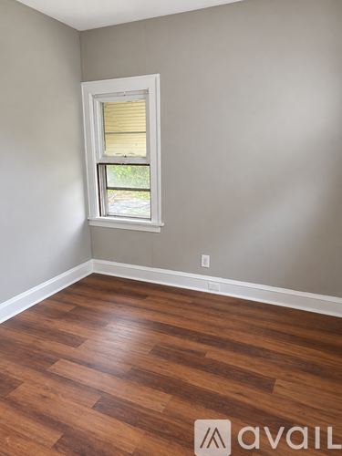 A room with a window and wooden flooring.