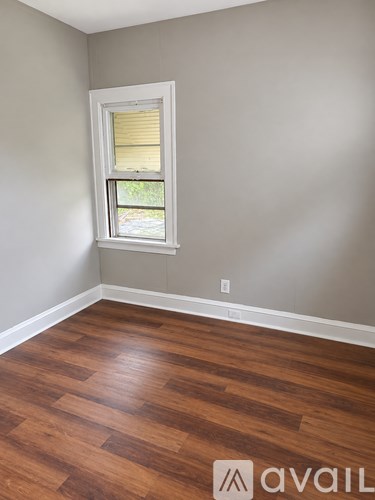 A room with a window and wooden flooring.