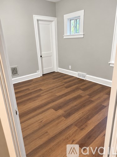 A room with wooden flooring and a white door.
