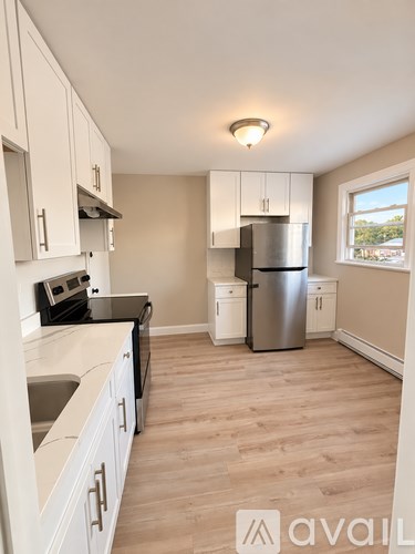 A kitchen with white cabinets and a wooden floor.