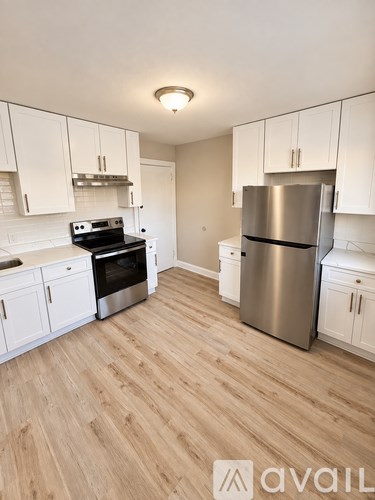 A kitchen with white cabinets and a wooden floor.