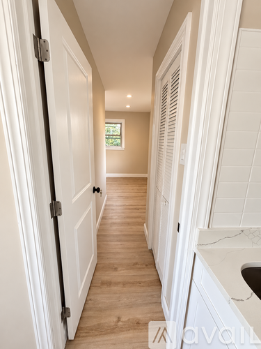 A hallway with white doors and a window.