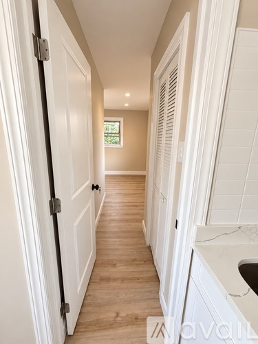 A hallway with white doors and a window.