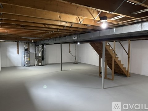 A spacious attic room with wooden beams and a staircase.