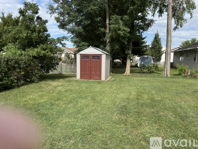 A red shed sits in a grassy yard.