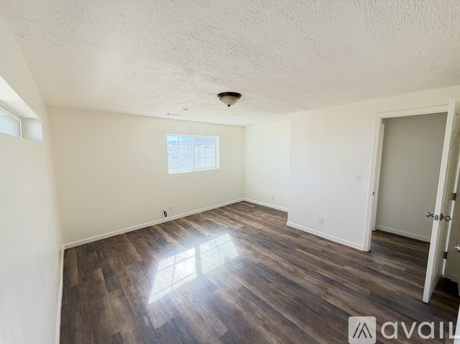 A room with wooden flooring and a window letting in sunlight.