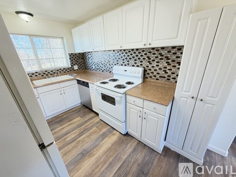 A kitchen with white cabinets and a black and white checkered backsplash.