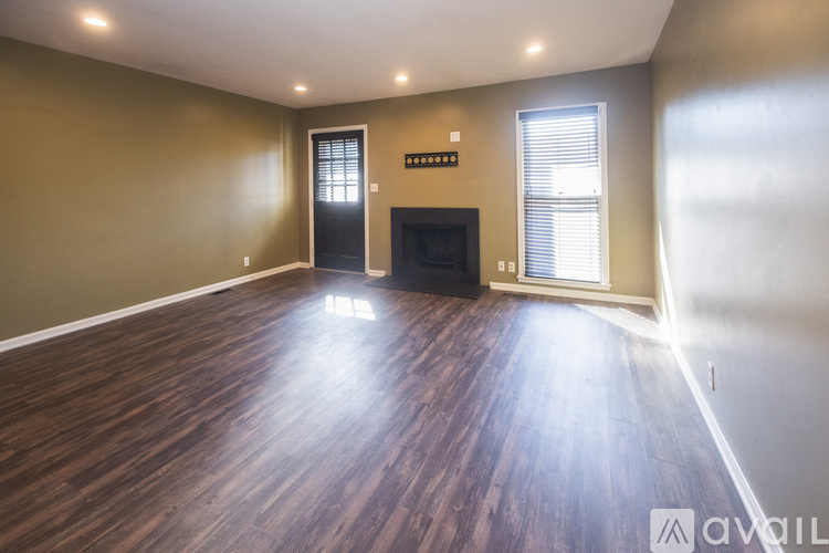 A spacious room with wooden flooring and a fireplace.