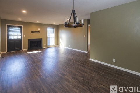 A spacious living room with wood flooring and a dark fireplace.