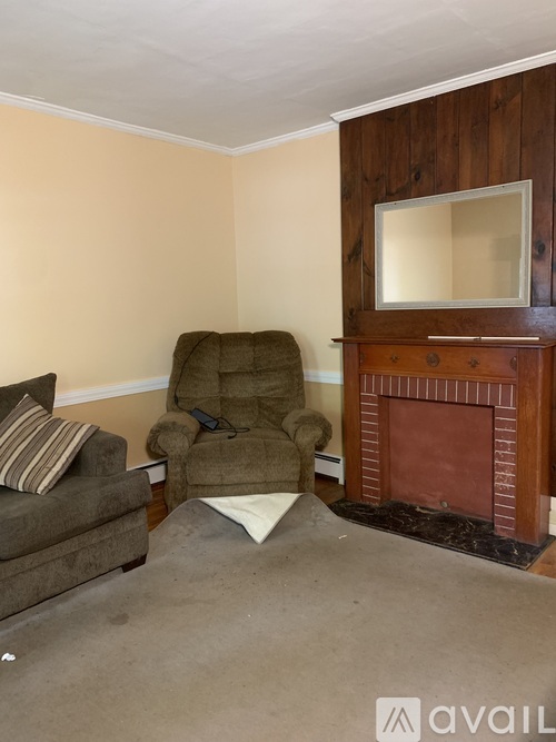A living room with a brown chair and a fireplace.