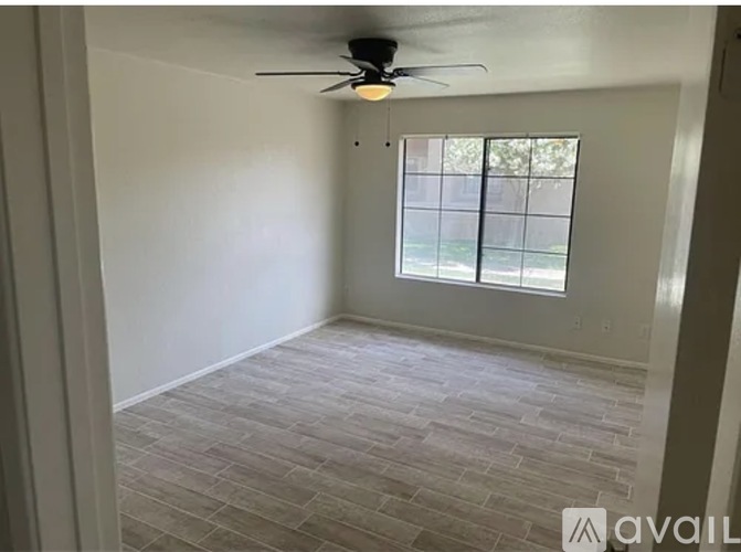 A room with a ceiling fan and a window with blinds.