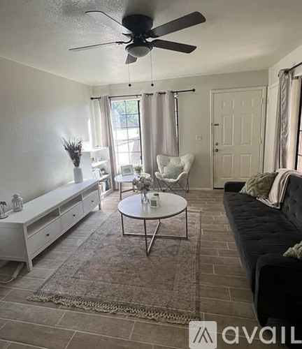 A living room with a black couch, a white coffee table, and a ceiling fan.