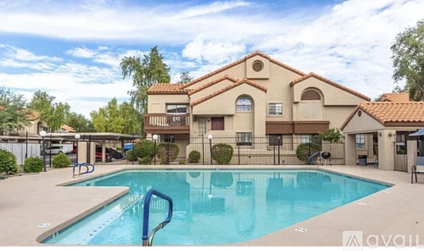 A swimming pool in front of a house with a blue sky and clouds in the background.