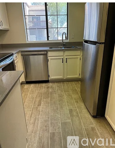 A kitchen with a refrigerator, sink, and cabinets.