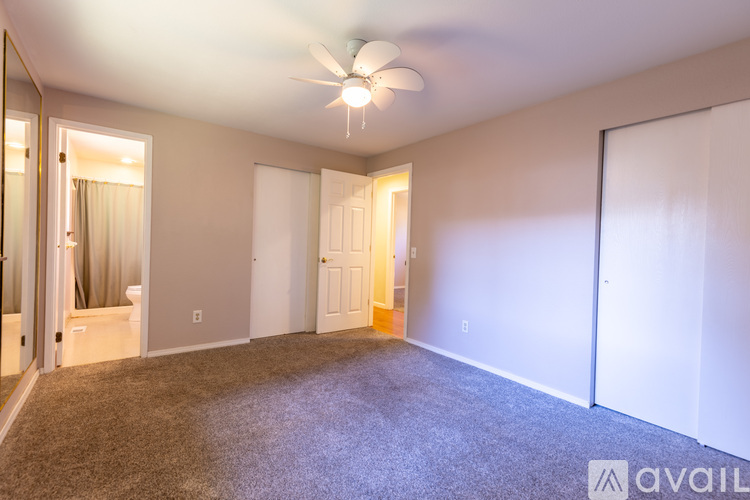 A spacious room with a ceiling fan and carpeted floor.