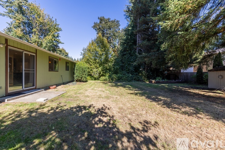 A backyard with a house, trees, and a lawn.