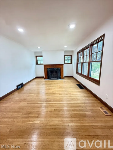 A spacious room with wooden flooring and a fireplace.