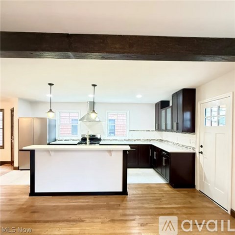 A kitchen with a white island and dark brown cabinets.