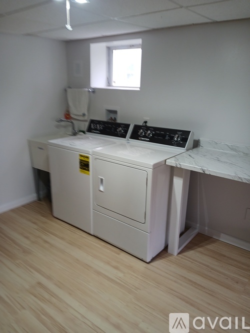 A white medical machine with a yellow sticker on it is in a room with wooden flooring.
