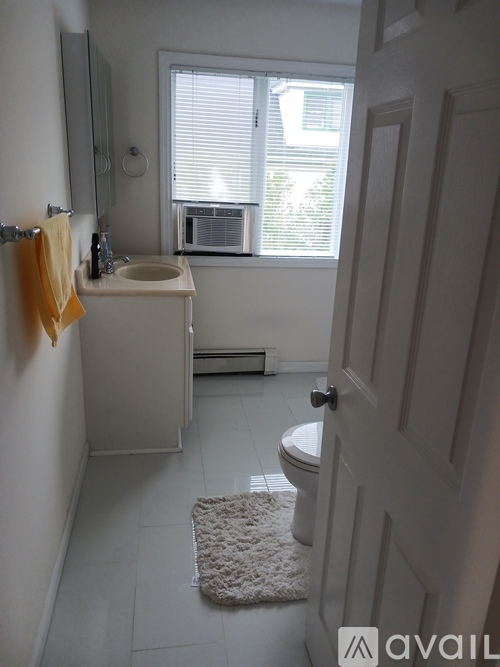 A bathroom with a toilet, sink, and window.