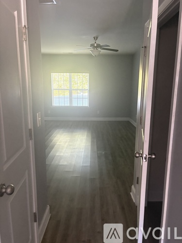 A hallway with a wooden floor and a ceiling fan.
