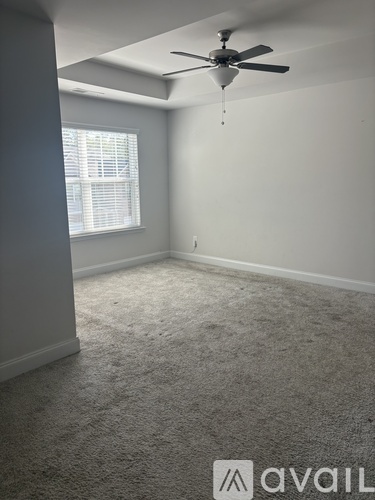 A room with a ceiling fan and carpeted floor.