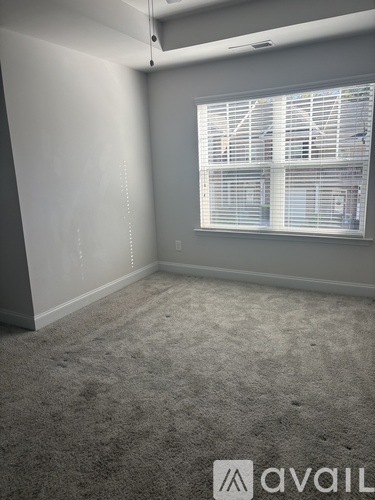 A room with a carpeted floor and a window with blinds.