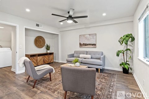 A living room with a grey couch, a chair, a coffee table, and a ceiling fan.