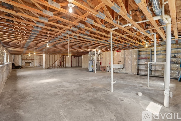 A spacious room with wooden beams on the ceiling and unfinished walls.