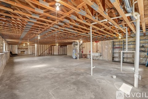 A spacious room with wooden beams on the ceiling and unfinished walls.