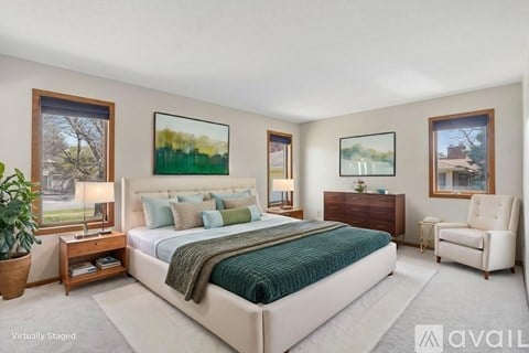 A bedroom with a large bed, a chair, and two pictures on the wall.
