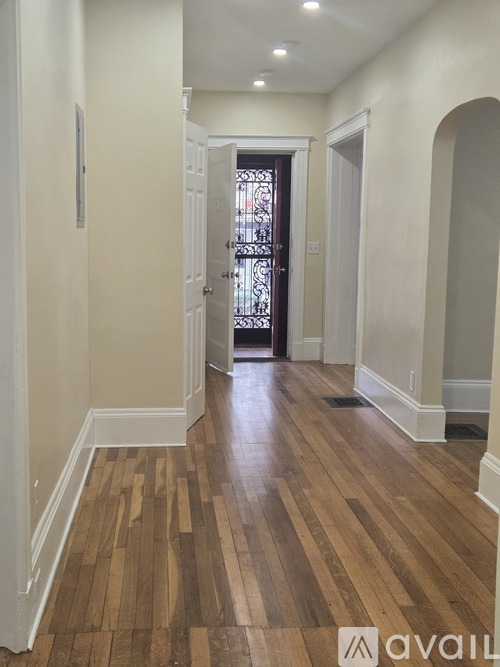 A hallway with wooden floors and white walls.