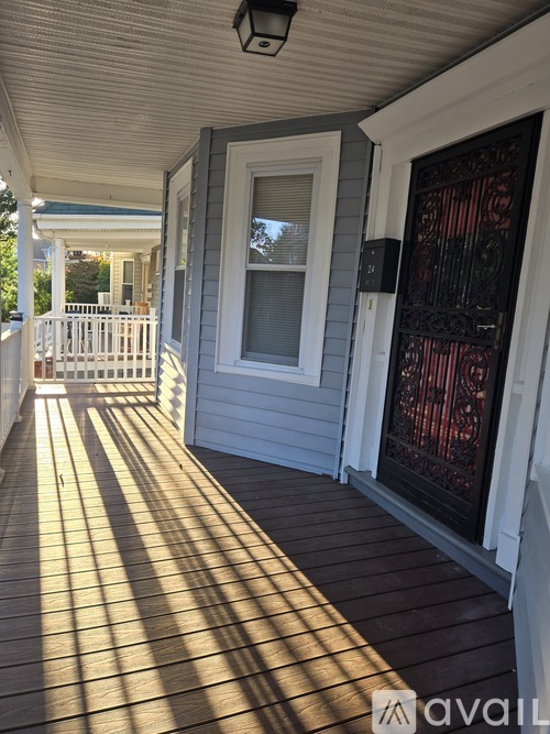 A wooden deck with a white railing and a door with a red curtain.