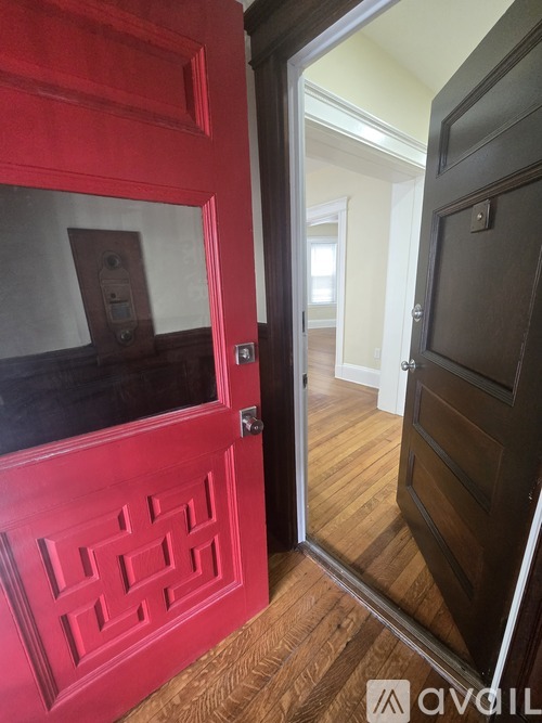 A red door with a decorative design on the side is open.