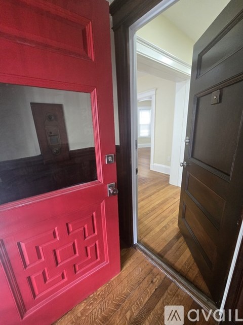 A red door with a decorative design on the side is open.
