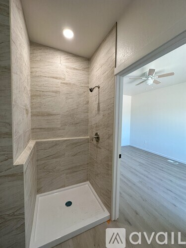 A bathroom with a tiled shower and a white tub.
