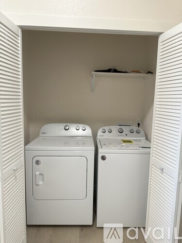 Two white front loading washing machines in a small laundry room.