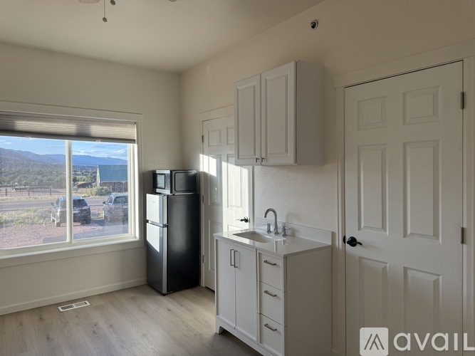 A kitchen with white cabinets and a black refrigerator.