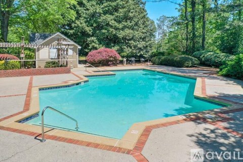 A pool surrounded by a brick border with a metal hand rail.