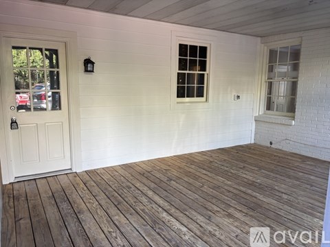A wooden deck with a white door and windows.