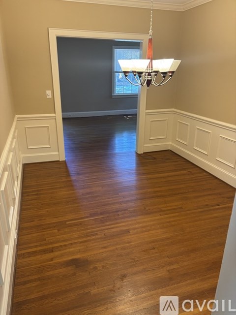 A hallway with wooden floors and a chandelier.