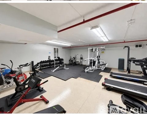 A gym with a variety of exercise equipment including treadmills, weights, and exercise machines.