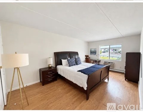A bedroom with a large bed, a lamp, and a nightstand.