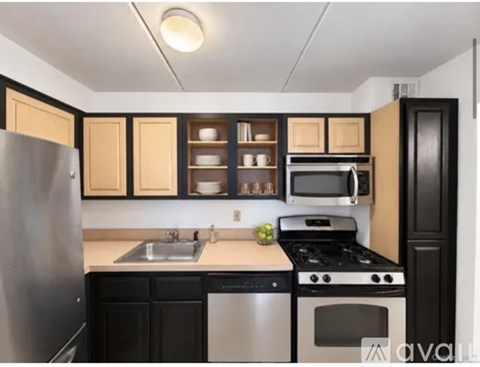 A kitchen with black cabinets and a stainless steel refrigerator.