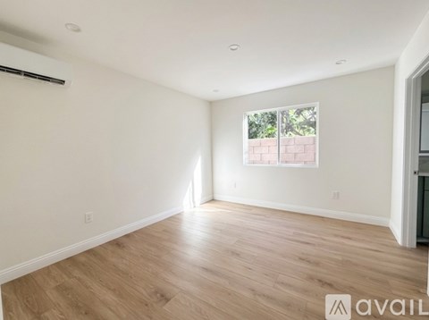 A spacious room with wooden flooring and a window.