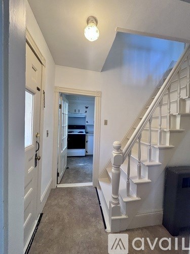 A hallway with a staircase leading to a kitchen.