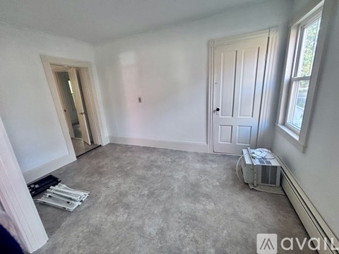 A room with a door, window, and a fan on the floor.