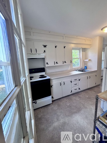 A kitchen with white cabinets and a black stove top oven.