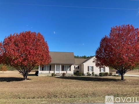 A house with two red trees in front of it.