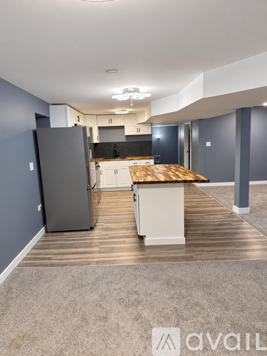 A kitchen area with a refrigerator, cabinets, and a countertop.